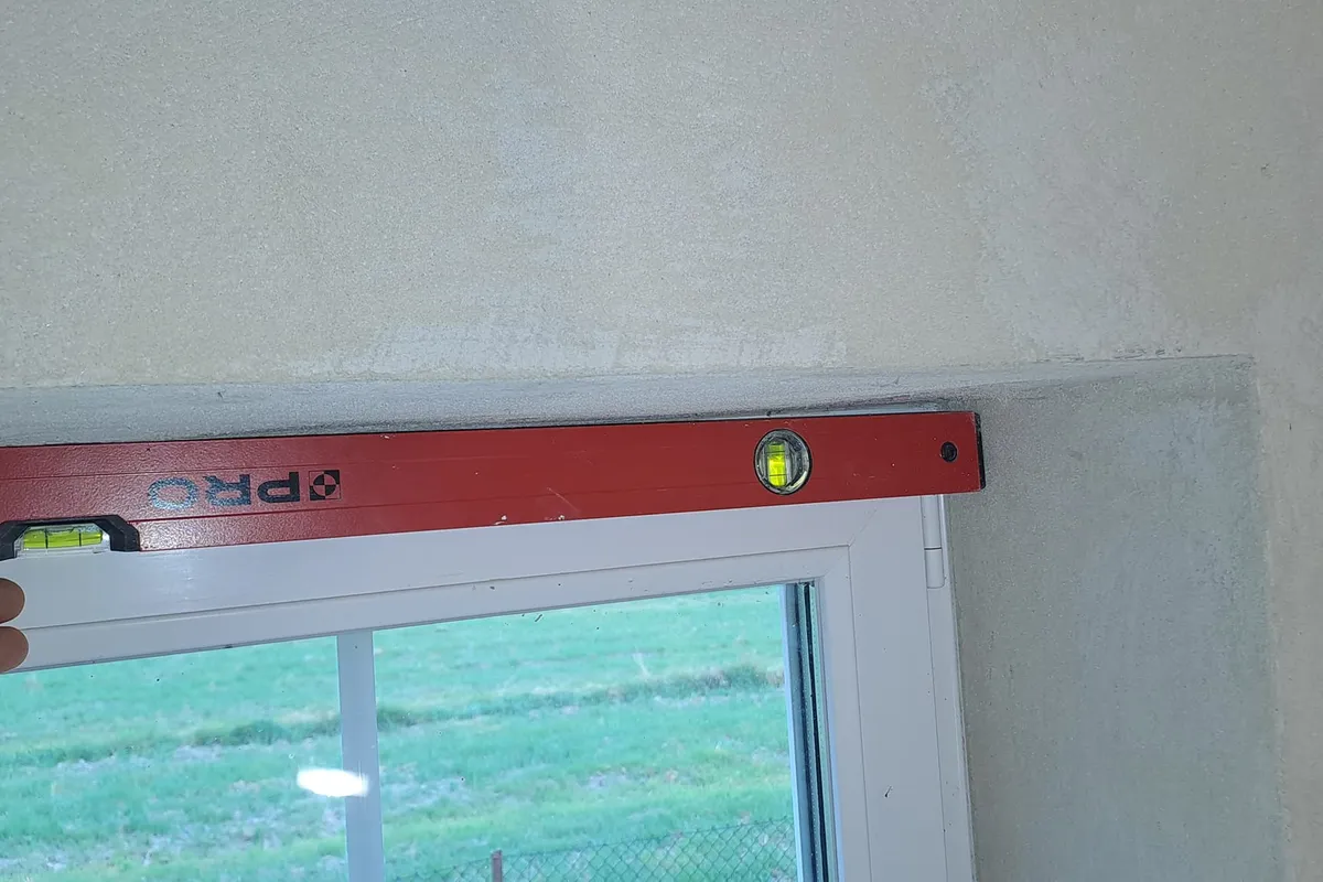 Pomiar płaszczyzny tynków łatą kontrolną - widoczna szczelina przekraczająca normę 3 mm